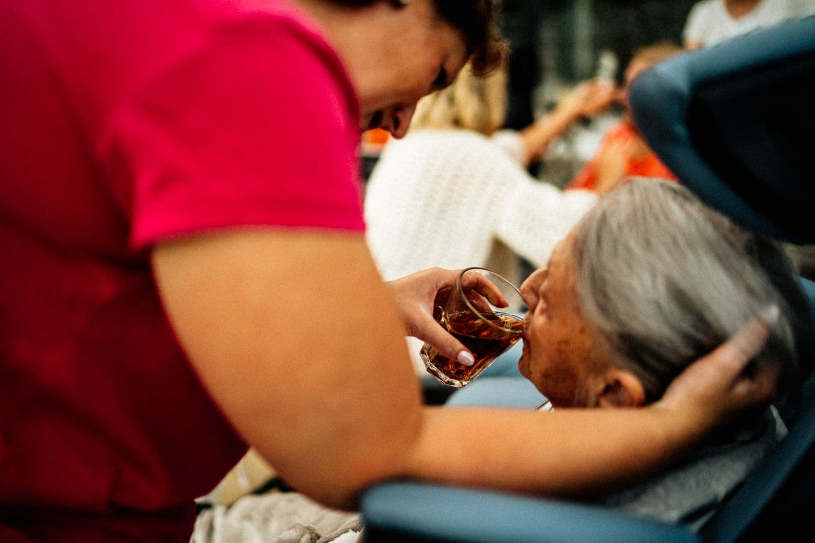 A support worker helping an older woman with a cup of tea