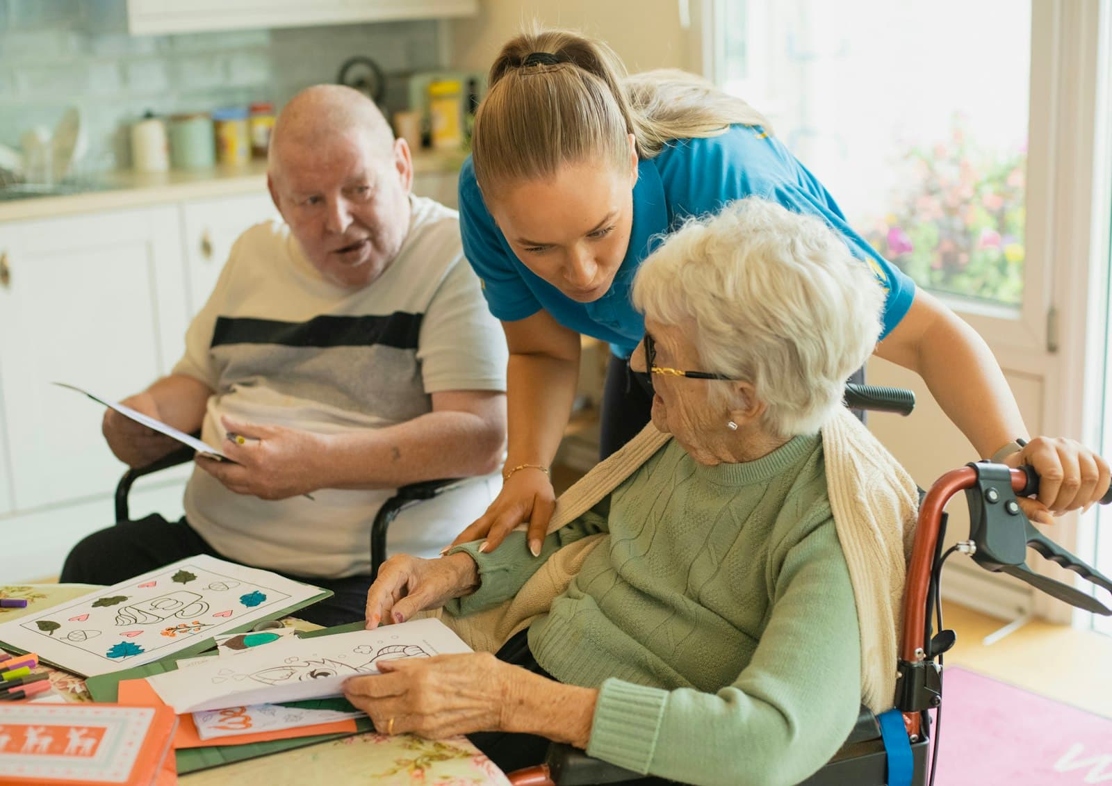 A support worker colouring in at a table with an older couple