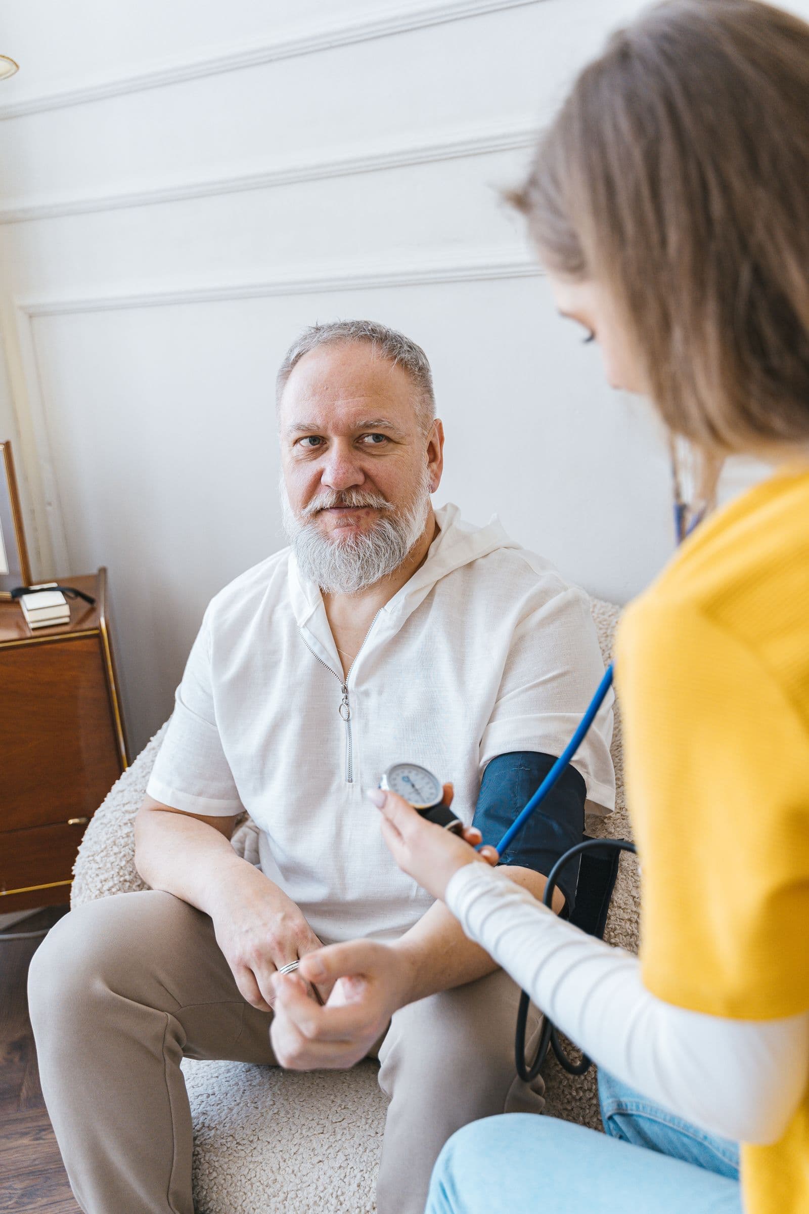 A nurse checking an older man's blood pressure at home